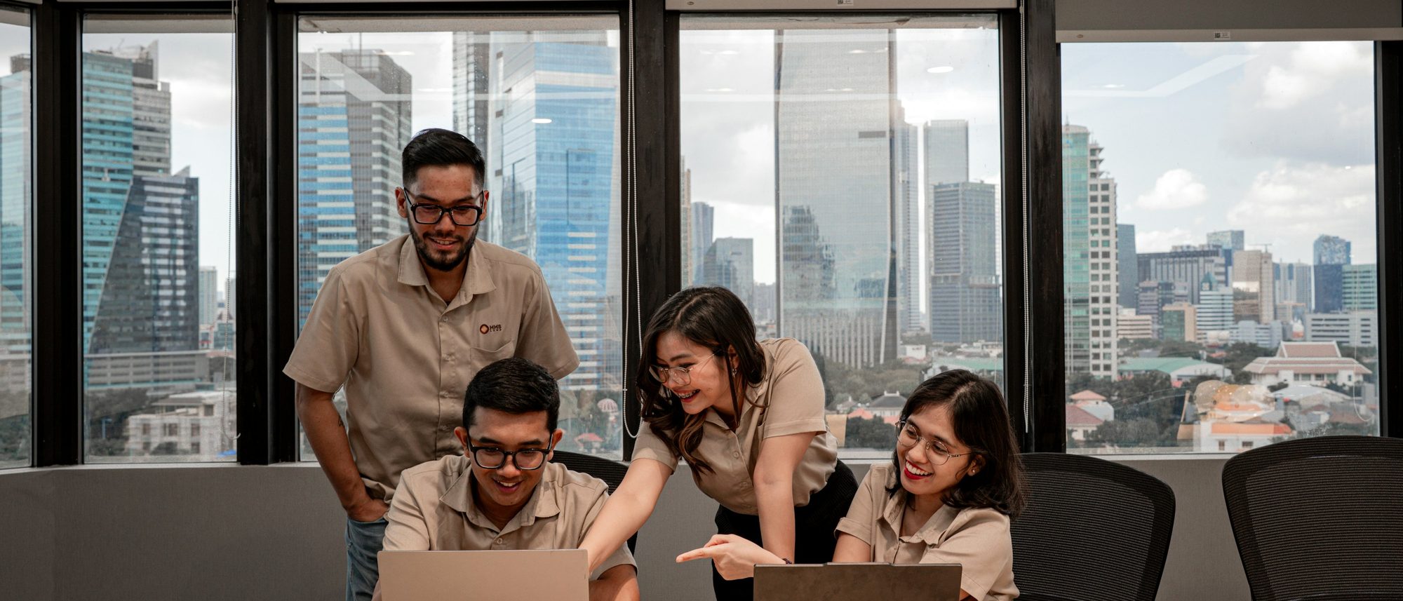 Equipe reunida em volta de notebooks em um escritório com vista para a cidade